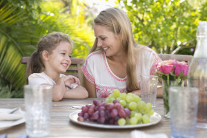 Mother and daughter smiling at table outdoors